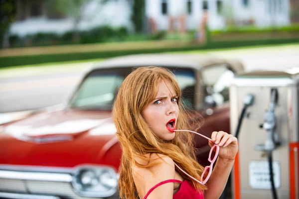 Βενζινάδικο. Όμορφη γυναίκα ανεφοδιάζει το αυτοκίνητο. Κομψή κυρία κατά του κόκκινου ρετρό αυτοκινήτου. — Φωτογραφία Αρχείου