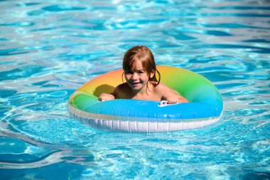 Yüzme havuzunda yüzen yüzme halkasıyla oynayan mutlu bir çocuk. Yaz tatili. Sağlıklı çocuk yaşam tarzı.
