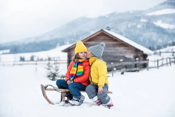 Kış çocukları pikniği. Karda kızakta oturmuş, sarılıp öpüşen romantik bir çift. Tatil sezonu başlıyor, birlikte dışarıda vakit geçiriyoruz. Çocuklar öpüşüyor.. — Stok fotoğraf