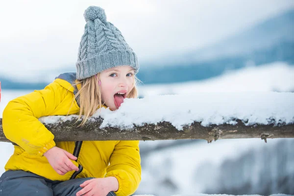 面白い子供たちは雪のフレークを食べる。子供は冬に雪を舐めて食べる。雪のフレークを持つ子供。コミカルな面白い顔. — ストック写真
