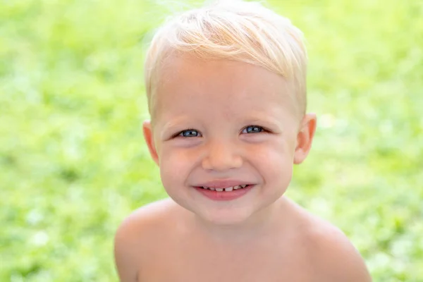 Fechar o rosto da criança sorrindo bonito primavera. Conceito de emoções infantis. Retrato de jovem rindo menino ao ar livre. — Fotografia de Stock