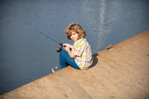 Pescador de niños pequeños. Pesca infantil en la orilla del río, actividad de ocio al aire libre de verano. Niño en la orilla del río con caña. Pescado. — Foto de Stock