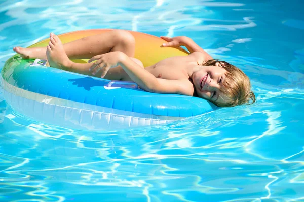 Kind in het zwembad spelen in het water. Vakantie en reizen met kinderen. Kinderen spelen in de zomer buiten. Kind met drijvende ring. — Stockfoto