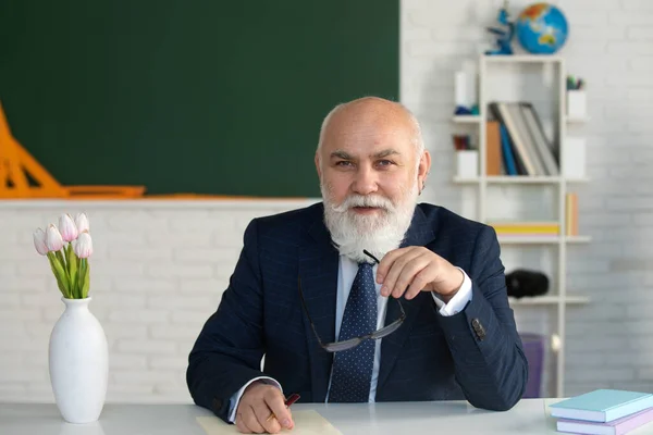 Senior academic professor on lecture near empty blackboard. Knowledge and traditional education concept.