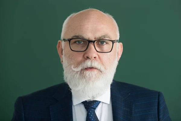 Closeup portrait of senior academic professor on lecture near empty blackboard. Knowledge and traditional education concept.