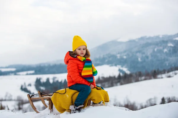 Winter child. Funny kid in snow sit on sled, sleigh. Child sledging outside in winter. — Stock Photo, Image