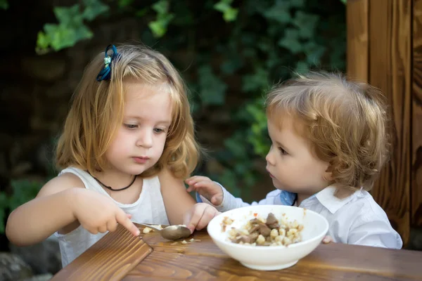 Nutrizione dei bambini. Ragazza che dà da mangiare al bambino. Sorella nutre fratello. Rapporti con i bambini. — Foto Stock
