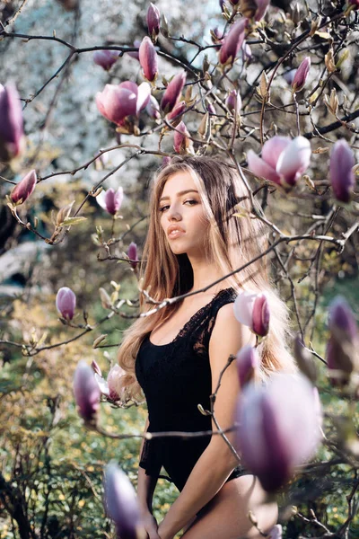 Nuori kaunis muodikas tyttö. Malli poseeraa kukassa magnoliassa. Kevään muoti käsite. — kuvapankkivalokuva