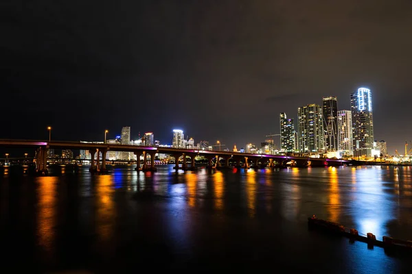 Miami éjszaka a belvárosban. Miami Florida, naplemente panoráma színes megvilágított üzleti és lakóépületek és híd Biscayne Bay. — Stock Fotó