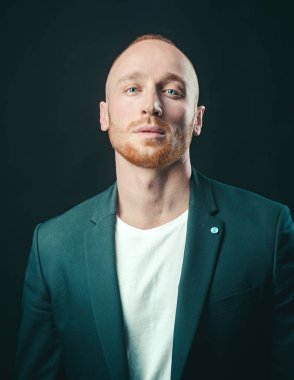 Kendine güvenen bir iş adamı. Genç adamın kameraya baktığı bir stüdyo fotoğrafı. Siyahta yakışıklı adam. Biçim ve eğilim.