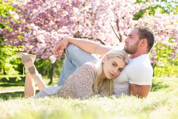 Jeune couple amoureux. Deux personnes se relaxant dans des fleurs de sakura. Mari et femme relation amoureuse. — Photo