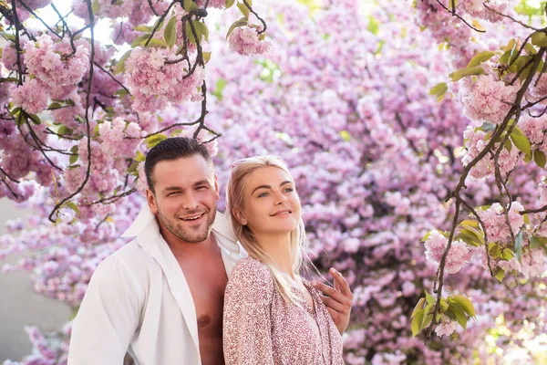 Gli amanti hanno momenti romantici. Coppia sensuale donna e uomo in fiori rosa nel parco dei fiori estivi. — Foto Stock