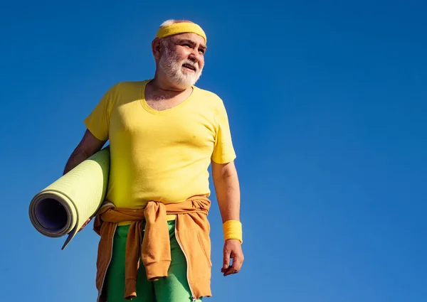 Senior man is doing fitness training. Funny sporty old sportsman finished his work out. Cheerful aged men holding yoga mats. Be in motion. — Stock Photo, Image