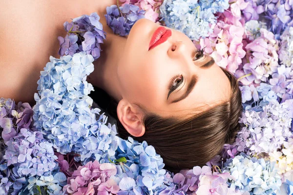 Nature beauty. Woman lying on flowers. Unity with nature. Blossom. Makeup cosmetics and skincare. Girl with hydrangea flowers. — Stock Photo, Image