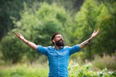 Yağmur yağıyor. Yaz yağmuru altındaki adam. Mutlu sakallı bir adamın tasviri. Yetişkin iyimserliği ve yalnız kalma zamanı..