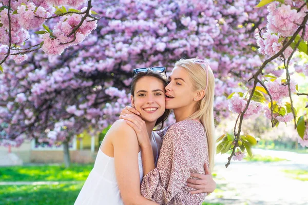 Meninas da primavera em flores. Retrato ao ar livre de jovem bonita feliz sorrindo casal feminino posando perto da árvore florida. — Fotografia de Stock