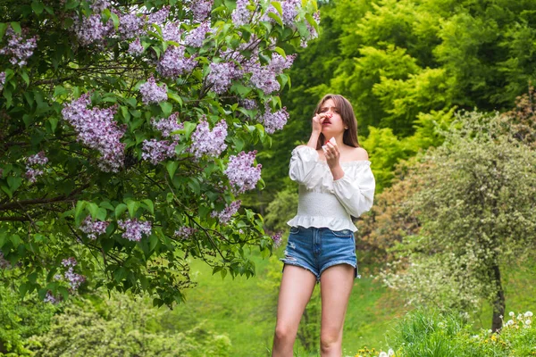 Alergia de primavera. Chica con la nariz estornuda. Concepto de síntoma alérgico. Mujer alérgica a la flor. — Foto de Stock