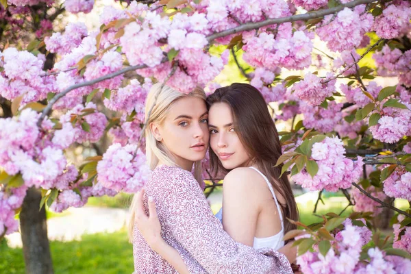 Две молодые чувственные сексуальные женщины расслабляются в цветах сакуры. — стоковое фото