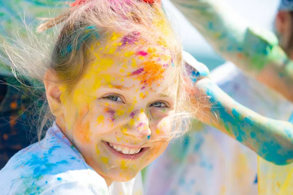 Festival de holi infantil. Cara pintada de chico gracioso. Niña juega con los colores. —  Fotos de Stock