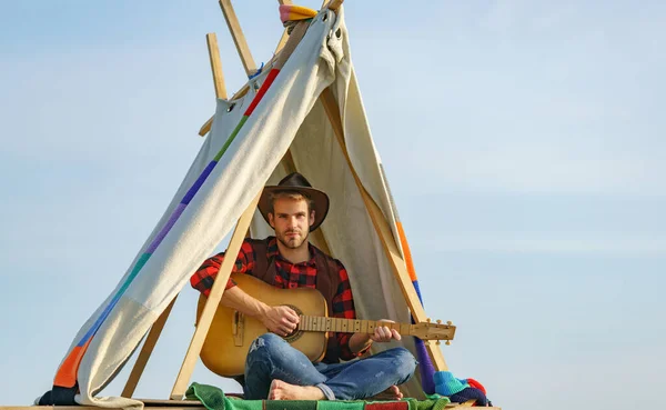 Bellissimo escursionista con chitarra in tenda. Cowboy maschio in campeggio. — Foto Stock