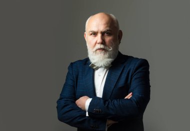 Kendinden emin iş adamı katlanmış silahlarla poz veriyor, kıdemli adam. Sakallı, orta yaşlı bir adamın portresi gri stüdyo arka planında fotokopi alanı olan bir adamın..