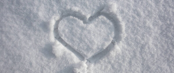 Heart on snow. Wintertime background. White background. Snow texture. Ice snowy background.