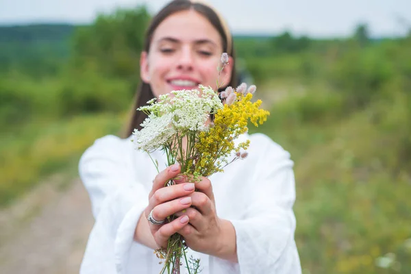 Primavera sorridente ragazza sul campo. Uno stile di vita sano. Donna nel prato con fiori di campo. Settore biologico. — Foto Stock