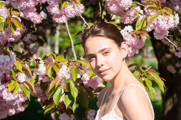 Girl in in blossoms cherry sakura. Outdoor portrait of beautiful sensual fashion girls posing near blooming tree with pink flowers. — Stock Photo, Image