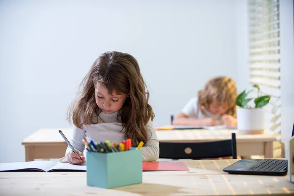 Zpátky do školy. Roztomilé psaní žáků na psacím stole ve třídě na základní škole. Studentka dělá test na základní škole. Děti píšou poznámky ve třídě během lekce. — Stock fotografie