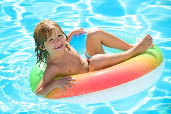 Bambini che nuotano con anello di nuoto. Ragazzo felice che gioca con anello di nuoto colorato in piscina il giorno d'estate. Giocattoli d'acqua per bambini. I bambini giocano in resort tropicale. Vacanza al mare in famiglia. — Foto Stock