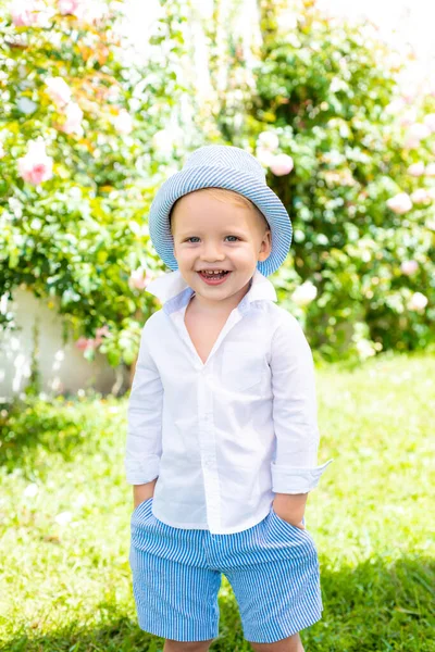 Criança feliz ao ar livre com chapéu ou panamá. As crianças de verão andam na roupa casual de parque. Garoto sorridente no parque da mola ou jardim, fundo borrão. — Fotografia de Stock