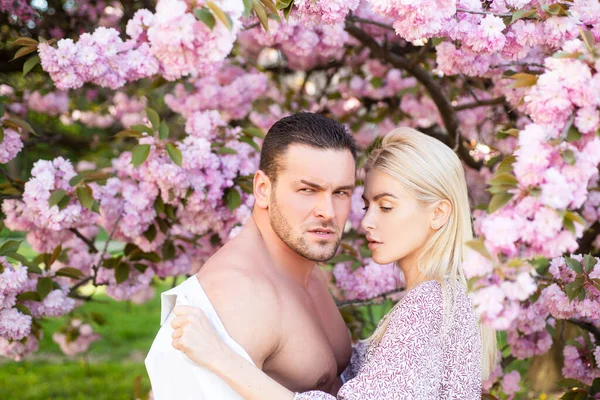 Zamilovaný jarní romantický pár hledící jeden na druhého. Vášnivý s nahým trupem. Smyslný pár v třešňových sakura květy. — Stock fotografie
