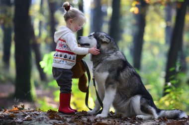 Çocuklar dışarıda köpekle oynuyorlar. Çocukluk, oyun ve eğlence. Aktivite ve aktif dinlenme. Ormanda köpeği olan küçük bir kız.