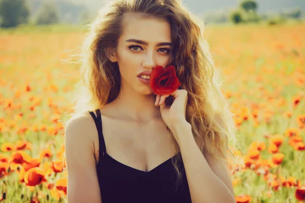 Flicka på vårfältet av vallmo. Utomhus porträtt av ung vacker kvinnlig modell poserar nära blommande natur. — Stockfoto