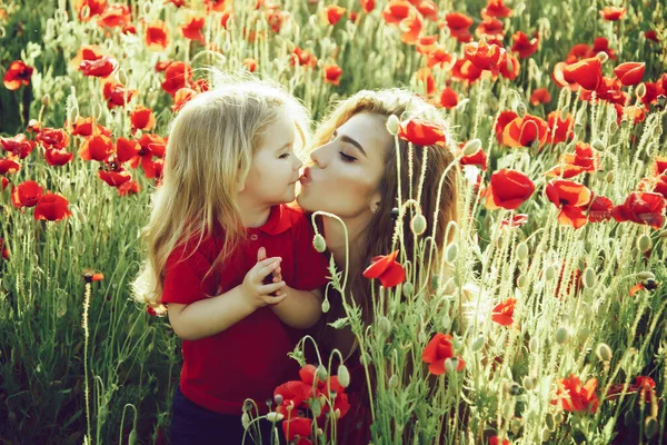 Roztomilá dívka a malý chlapec nebo dítě v poli máku. Jarní pusa. — Stock fotografie