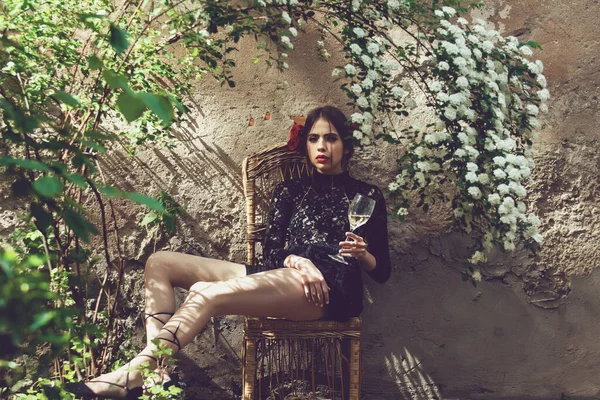 Mulher da Primavera. Menina ou mulher bonita, modelo jovem na moda com vidro de vinho sob flores florescentes em quintal ensolarado ao ar livre. — Fotografia de Stock