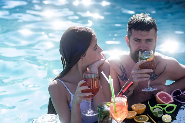 夏日情侣与鸡尾酒和水果一起在海里游泳。在马尔代夫的男人和女孩的鸡尾酒尾巴。泳池派对在温泉度假胜地休息. — 图库照片