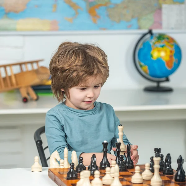 Kids early development. Nice concentrated little boy sitting at the table and playing chess. — Stock Photo, Image