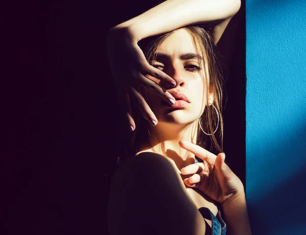 Ansikte av flicka med brunett hår och ingen makeup i solljus på blå bakgrund, skönhet och mode. — Stockfoto