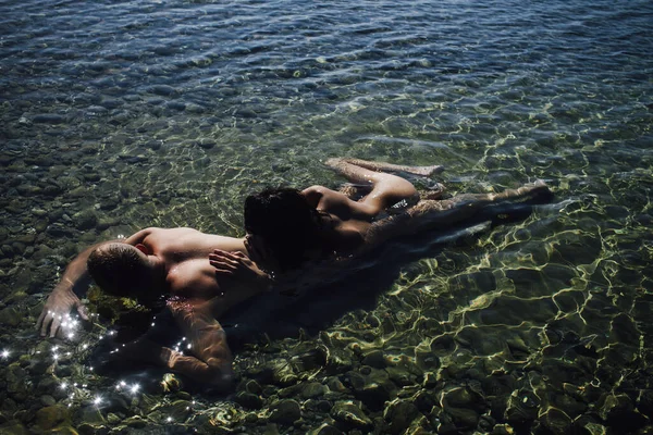 A sexy young couple embracing in summer sea water. — ストック写真