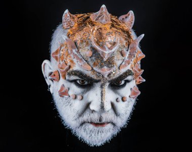 Dikenli kafa, yaklaş. İblis, büyücü makyajı. Fantezi konsepti. Ciddi yüzlü şeytan, siyah arkaplan.