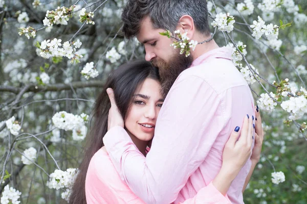 Ett par förälskade på vårdejten nära blommande träd. Man och kvinna kramar i blommande trädgård på vårdagen. — Stockfoto