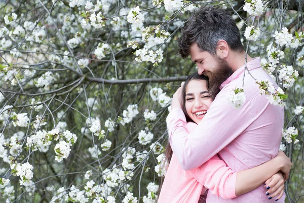 Vårdejtskoncept. Några kramar nära blommande träd. Par i kärlek kramar i blommande trädgård på våren dag. — Stockfoto