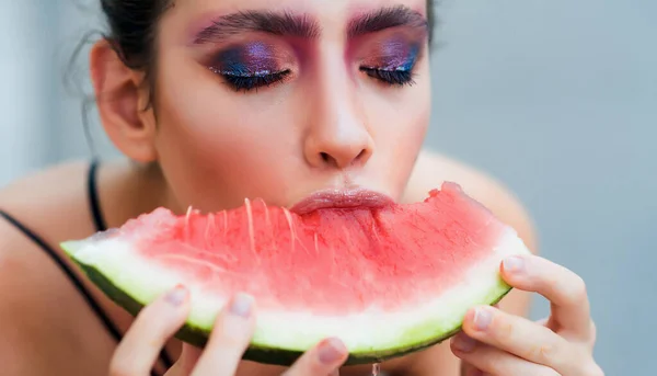 Женщина с макияжем и красной дыней. Молодая девушка ест сочный арбуз. Красавица, смотри, визаж. Лето, фрукты, сезон урожая. — стоковое фото