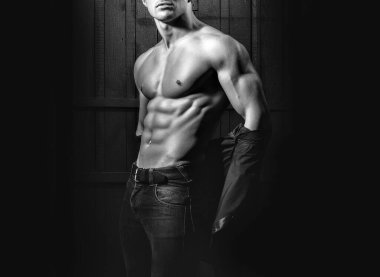 Stüdyoda ahşap arka planda güzel kaslı göğüslü genç seksi bir adam. Seksi gay..