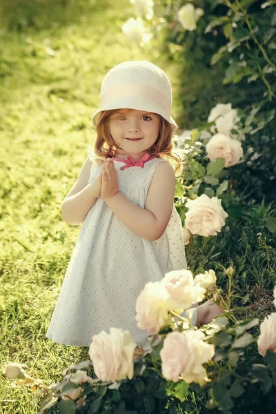 Inocencia, pureza y concepto juvenil. Niña con sombrero sonriendo con las manos en oración en el jardín de verano. Germinación y crecimiento. Futuro y florecimiento. —  Fotos de Stock