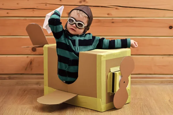 Pilot latający kartonowym pudełkiem na drewnianym tle. Marzenie dziecka. — Zdjęcie stockowe