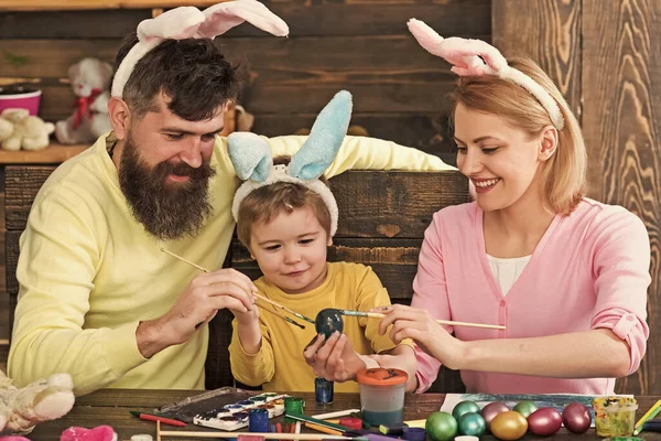 Mutlu aile için Paskalya yumurtası fikirleri. Anne, baba ve oğul Paskalya yumurtalarını tavşan kostümü ve kulaklarıyla boyuyorlar.. — Stok fotoğraf