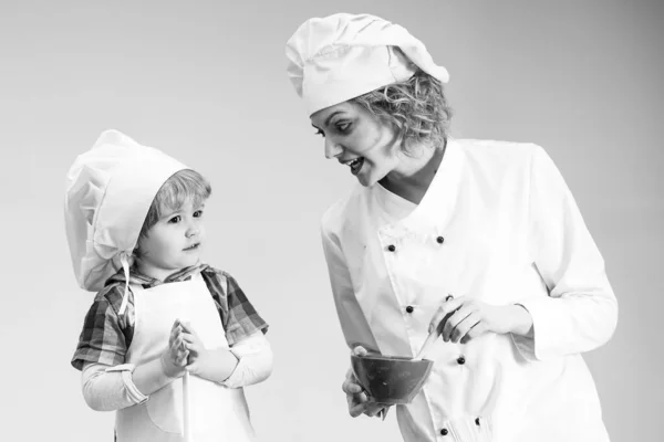 Mãe ensina filho a cozinhar. Mãe e criança com rosto ocupado cozinhar alimentos juntos. — Fotografia de Stock