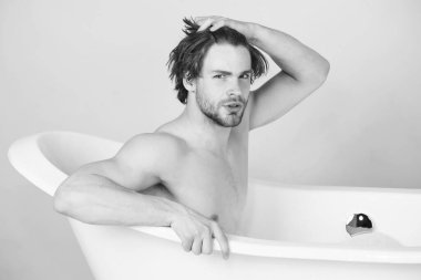 Küvette oturan yakışıklı adam. Küvetteki adam. Spa ve güzellik, rahatlama ve hijyen, sağlık hizmetleri. Siyah beyaz.